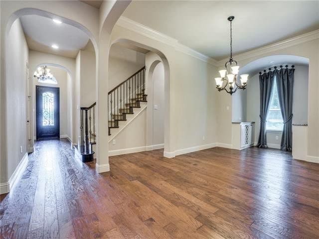 foyer with ornamental molding, dark hardwood / wood-style flooring, and a chandelier