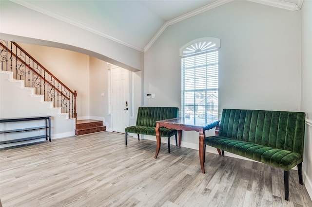 sitting room featuring lofted ceiling, light wood-type flooring, and ornamental molding