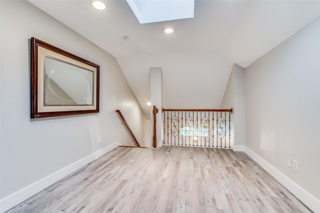 interior space with light hardwood / wood-style floors and vaulted ceiling with skylight