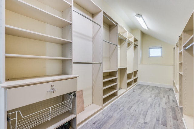 walk in closet with light hardwood / wood-style floors and vaulted ceiling