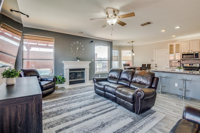 living room featuring a healthy amount of sunlight, light wood-type flooring, and ornamental molding