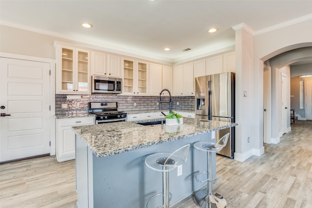 kitchen with light stone countertops, appliances with stainless steel finishes, a breakfast bar, sink, and an island with sink