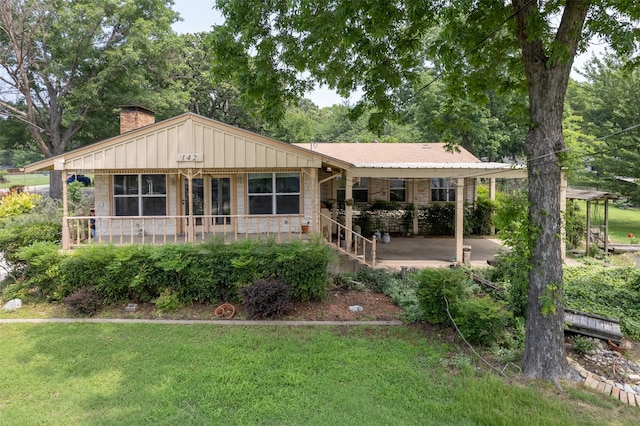 rear view of property featuring a porch, a lawn, and a carport