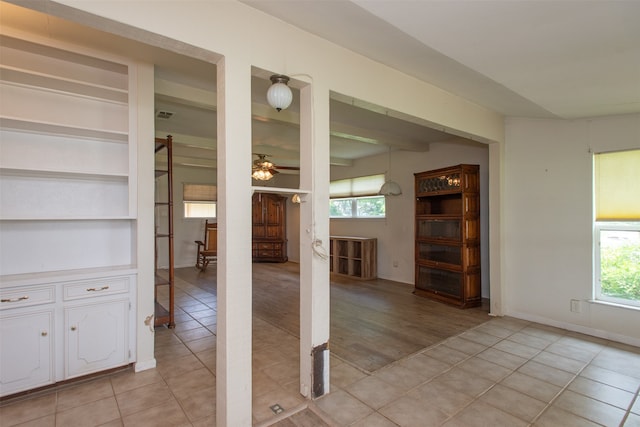 unfurnished dining area featuring a healthy amount of sunlight, ceiling fan, and light tile patterned floors