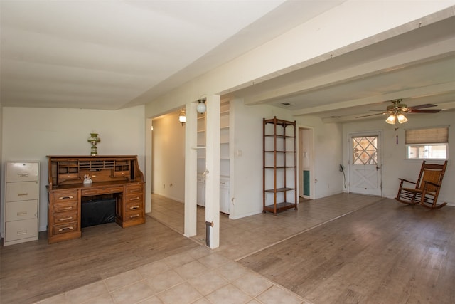 unfurnished living room featuring beamed ceiling, ceiling fan, and light hardwood / wood-style flooring