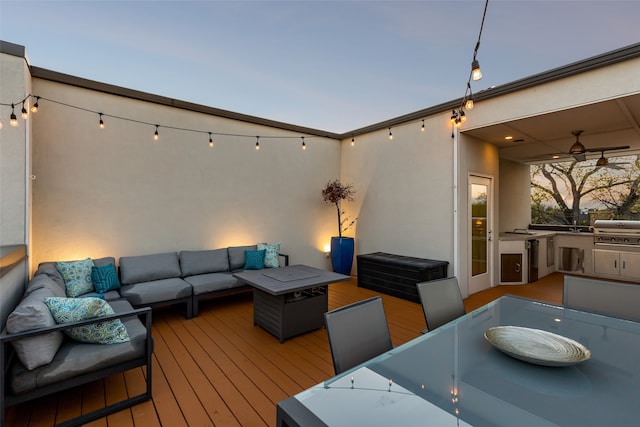 deck at dusk with an outdoor hangout area and grilling area