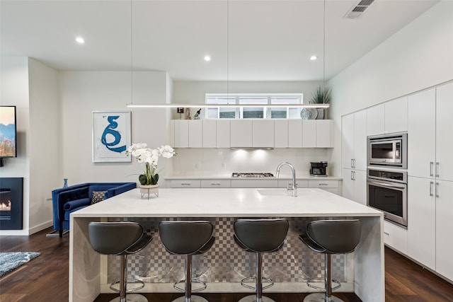 kitchen featuring an island with sink, appliances with stainless steel finishes, and a kitchen breakfast bar