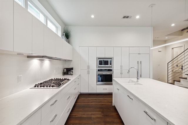 kitchen featuring appliances with stainless steel finishes, dark hardwood / wood-style floors, sink, and white cabinetry