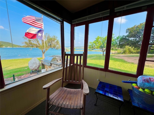 sunroom featuring a water view