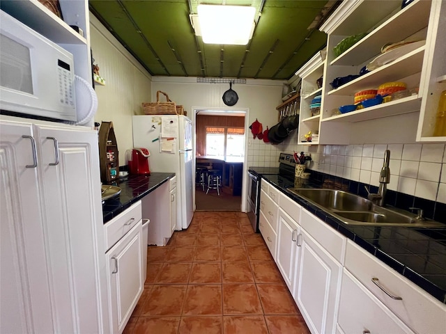 kitchen with white cabinets, light tile patterned flooring, sink, tasteful backsplash, and appliances with stainless steel finishes