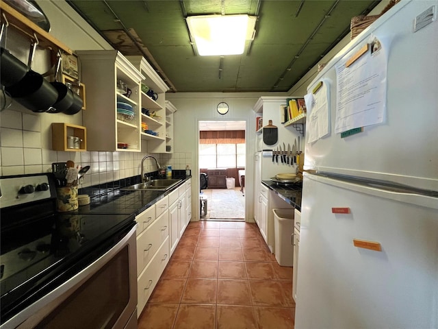 kitchen featuring dark countertops, open shelves, stainless steel range with electric cooktop, a sink, and freestanding refrigerator