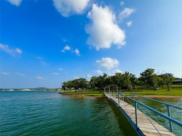 view of dock with a yard and a water view