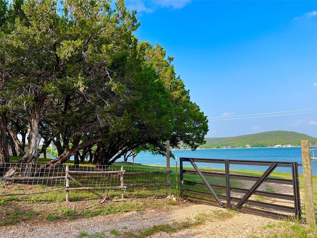 view of gate with a water view and fence