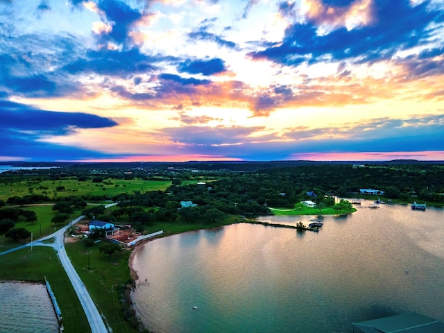 aerial view at dusk featuring a water view