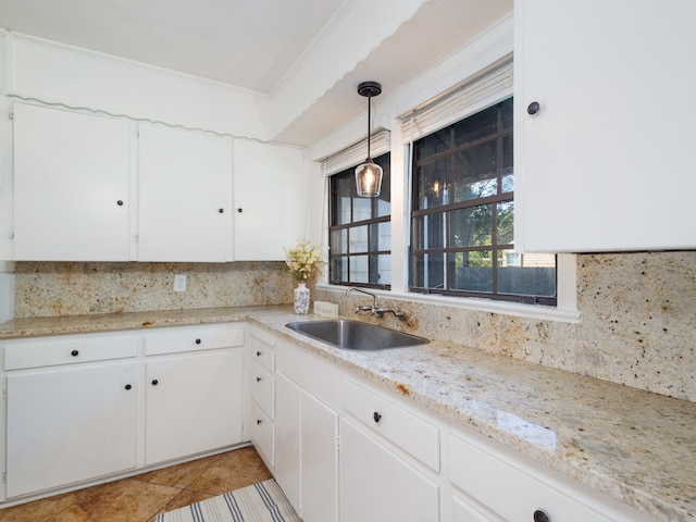 kitchen featuring hanging light fixtures, crown molding, white cabinetry, and sink