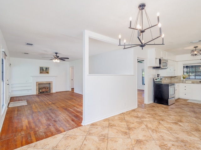 kitchen featuring light wood-type flooring, ceiling fan, white cabinets, a tile fireplace, and appliances with stainless steel finishes