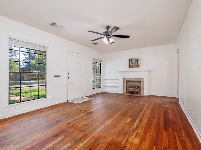 unfurnished living room featuring ceiling fan, dark wood-type flooring, and a tile fireplace