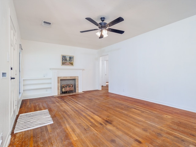 unfurnished living room featuring ceiling fan, hardwood / wood-style floors, and a tiled fireplace