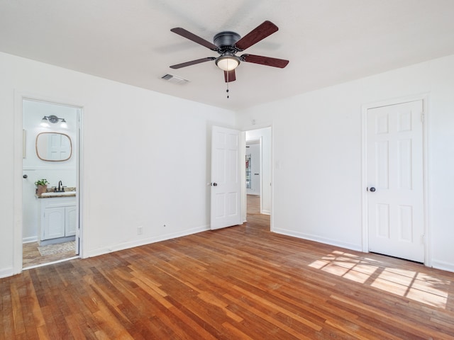 unfurnished bedroom with ceiling fan, hardwood / wood-style floors, and ensuite bathroom