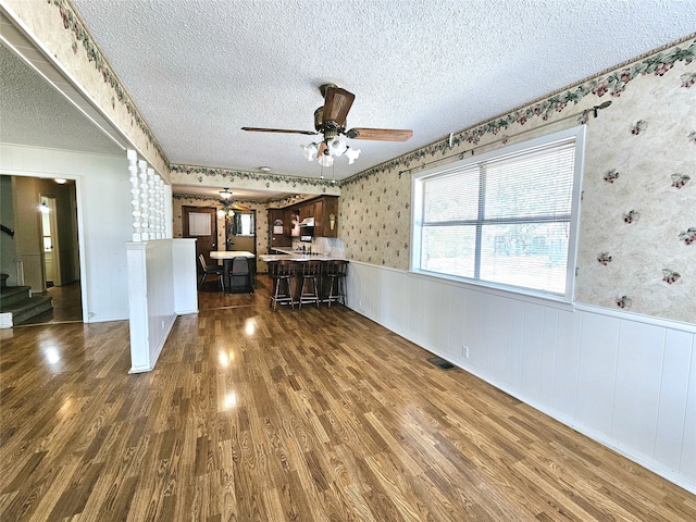 unfurnished living room with ceiling fan, a textured ceiling, and dark wood-type flooring