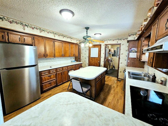 kitchen featuring ceiling fan, stainless steel refrigerator, sink, and wood-type flooring