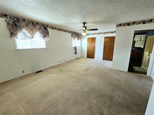 unfurnished bedroom featuring carpet flooring, multiple closets, a textured ceiling, and ceiling fan