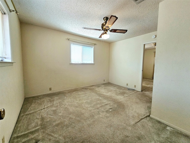 spare room with ceiling fan, a textured ceiling, and light carpet