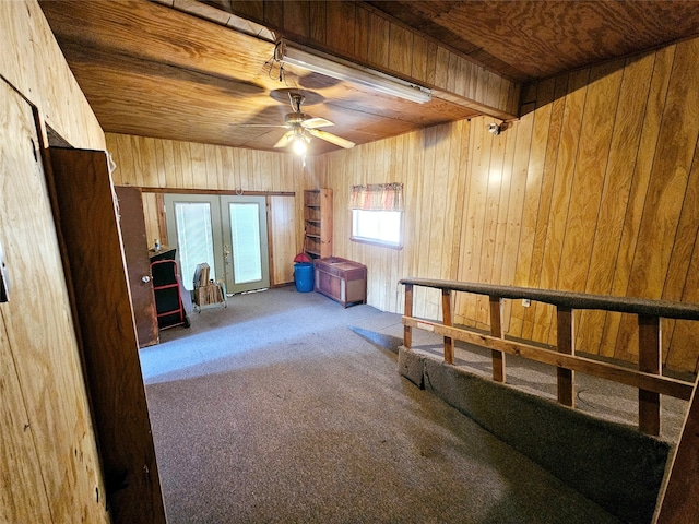 interior space featuring beamed ceiling, ceiling fan, wood ceiling, wood walls, and carpet