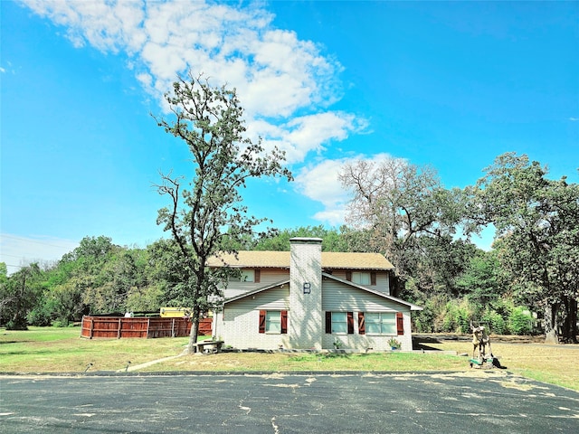 view of front of home featuring a front lawn, brick siding, and a chimney