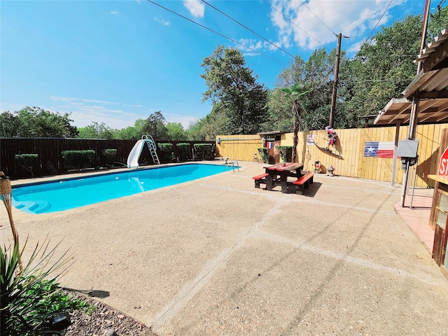 view of swimming pool featuring a water slide and a patio area