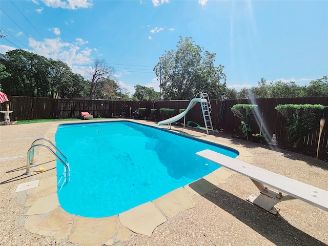 view of swimming pool featuring a water slide and a diving board