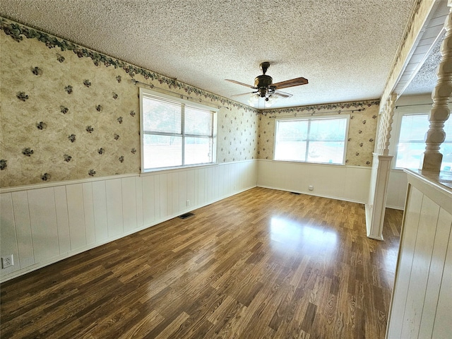 empty room with ceiling fan, dark hardwood / wood-style floors, wooden walls, and a textured ceiling