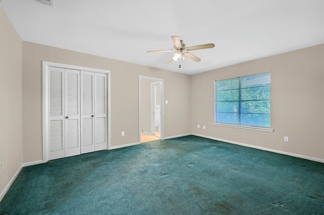 unfurnished bedroom featuring a closet, dark colored carpet, ensuite bath, and ceiling fan