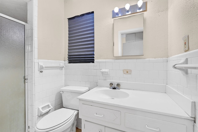 bathroom with an enclosed shower, tile walls, vanity, and toilet