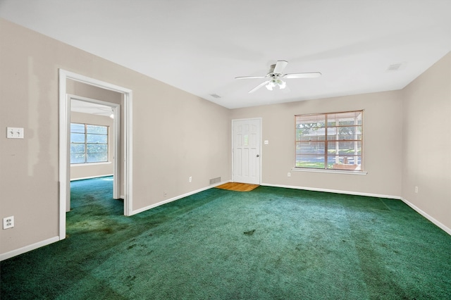 unfurnished room with ceiling fan, dark colored carpet, and a healthy amount of sunlight