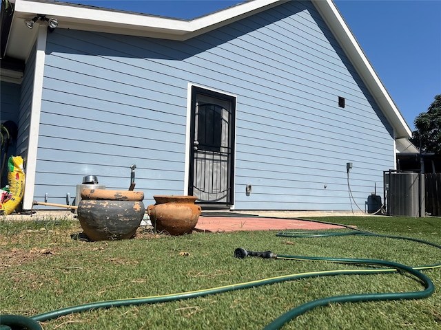 view of side of home featuring cooling unit and a lawn