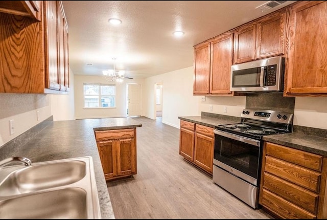 kitchen with stainless steel appliances, sink, light hardwood / wood-style floors, a notable chandelier, and a textured ceiling