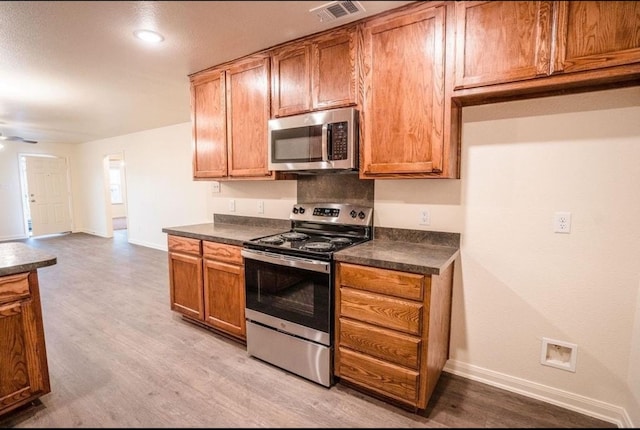 kitchen featuring ceiling fan, stainless steel appliances, and light hardwood / wood-style floors