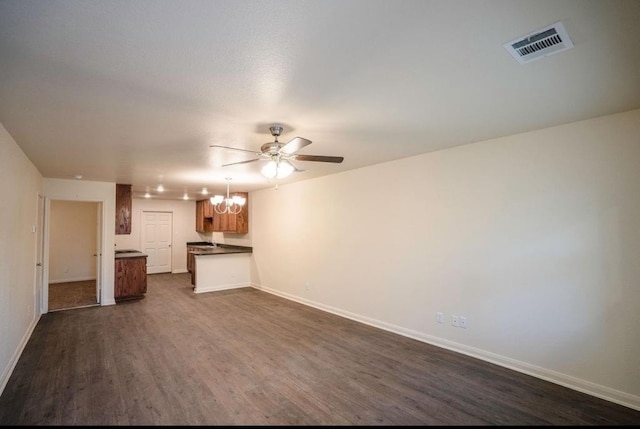 unfurnished living room featuring ceiling fan with notable chandelier and dark hardwood / wood-style flooring