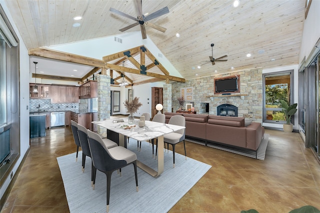 dining space with wood ceiling, high vaulted ceiling, sink, and a stone fireplace