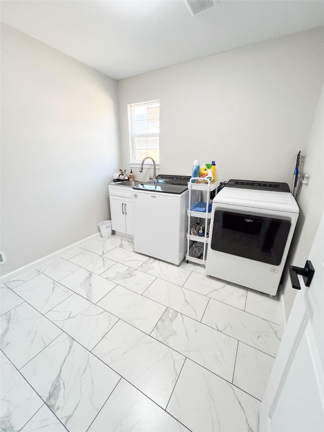 washroom with cabinets, washer and clothes dryer, and sink