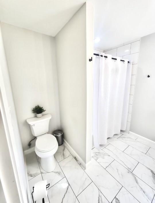 bathroom with curtained shower and toilet