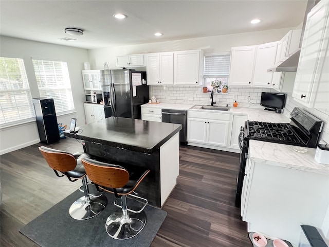 kitchen featuring stainless steel dishwasher, sink, dark hardwood / wood-style flooring, black fridge, and white cabinetry