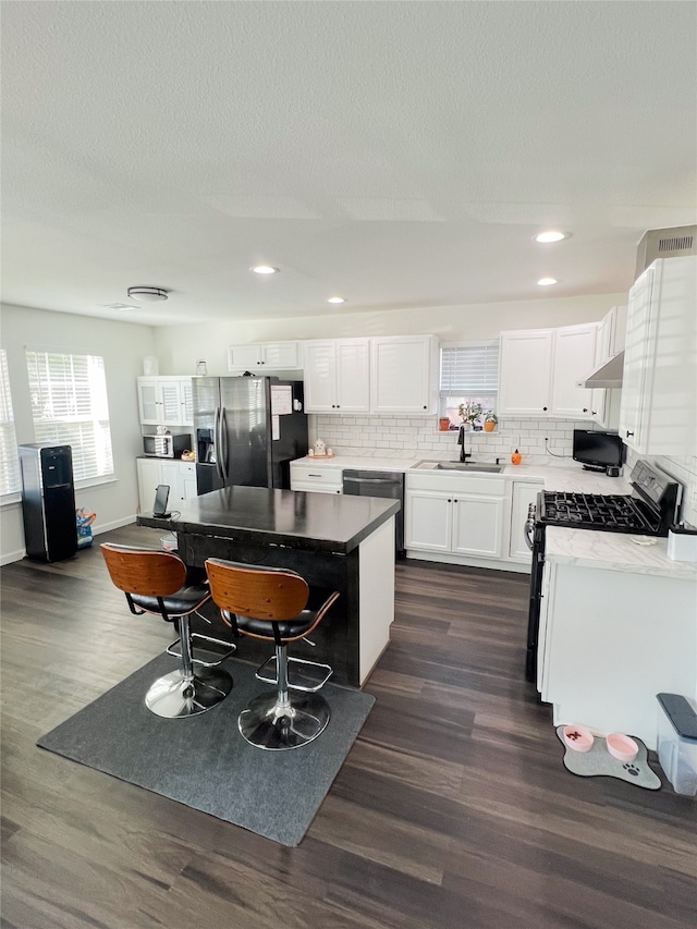 kitchen featuring sink, stainless steel appliances, dark hardwood / wood-style floors, a center island, and white cabinetry