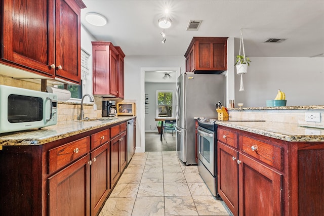 kitchen with light stone countertops, stainless steel appliances, sink, and decorative backsplash