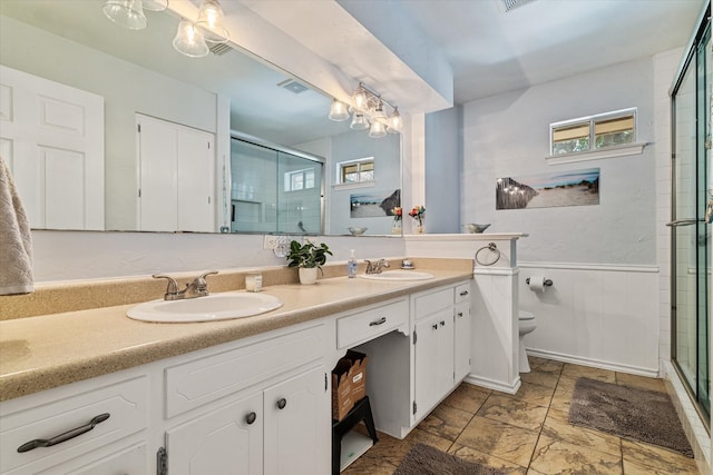 bathroom with vanity, toilet, and a shower with door