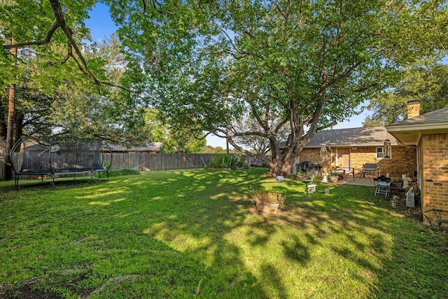 view of yard featuring a trampoline and a patio