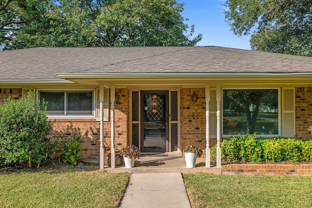 view of exterior entry with covered porch and a lawn