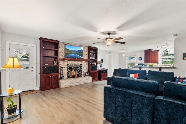 living room featuring ceiling fan, light wood-type flooring, and a fireplace