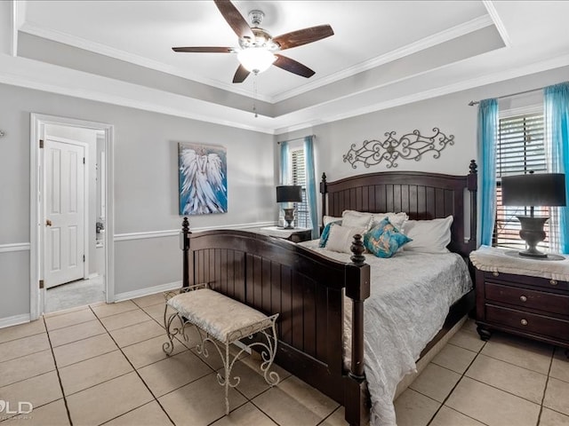 tiled bedroom featuring ornamental molding, multiple windows, ceiling fan, and a tray ceiling